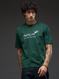 Bottle green recycled oversized T-shirt by Rudrajap with "Go With The Flow" embroidery, displayed on a plain background.