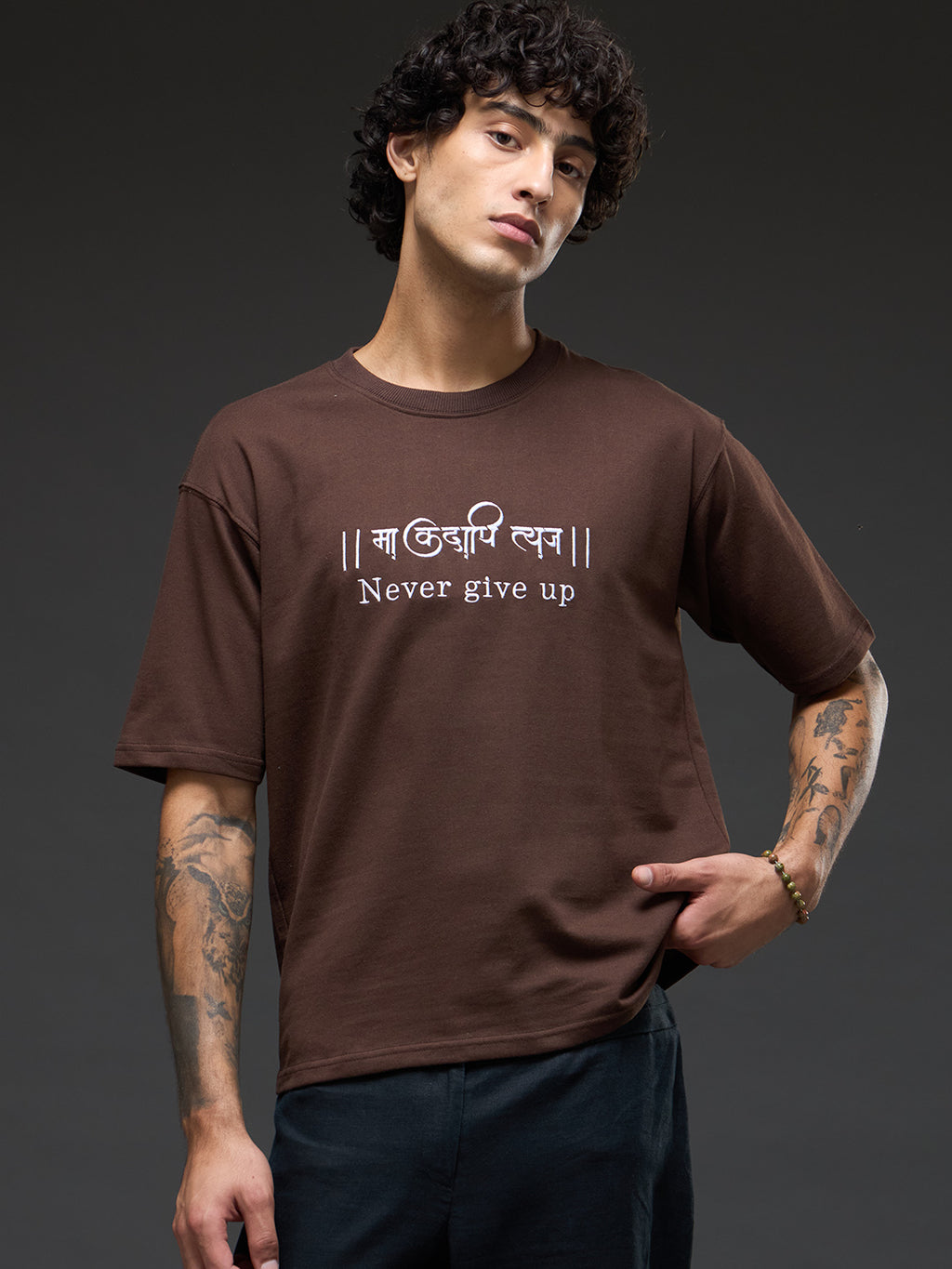Brown recycled oversized T-shirt by Rudrajap with "Never Give Up" embroidery, showcasing relaxed fit and eco-friendly fabric.