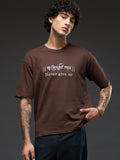 Brown recycled oversized T-shirt by Rudrajap with "Never Give Up" embroidery, showcasing relaxed fit and eco-friendly fabric.