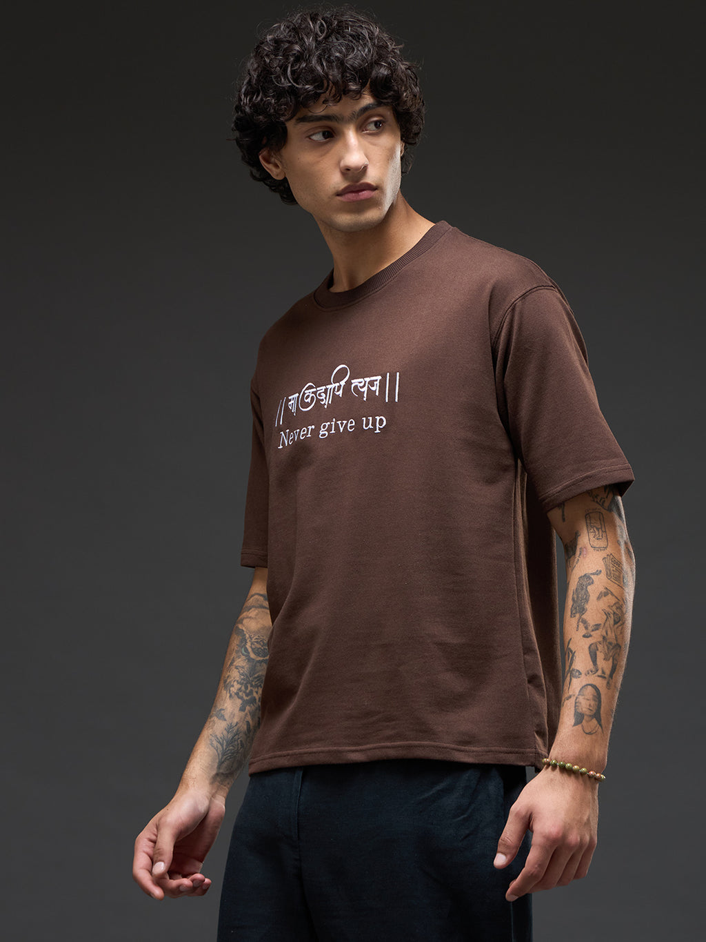 Brown recycled oversized T-shirt by Rudrajap with "Never Give Up" embroidered text, casual fit and eco-friendly material.