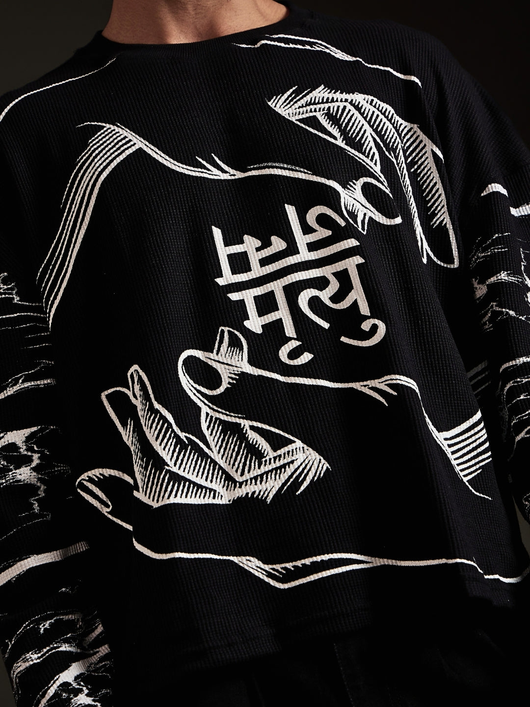 Close-up of जन्म मृत्यु lettering between two hands on black waffle fabric
