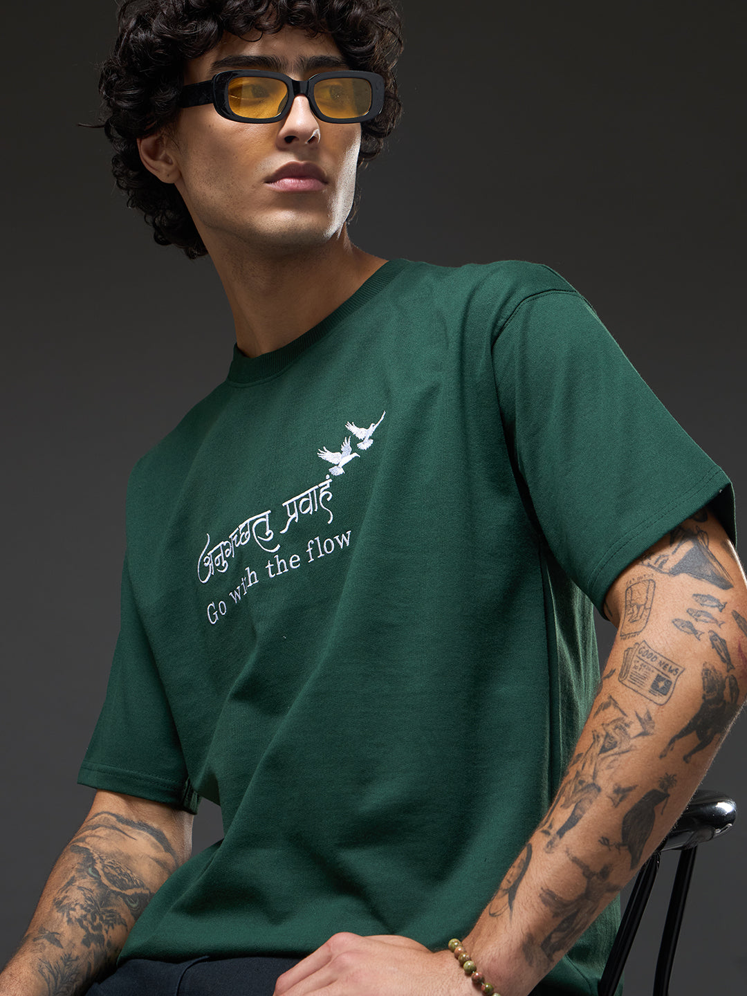 Bottle green recycled oversized T-shirt from Rudrajap with "Go With The Flow" embroidery, displayed on a flat lay.